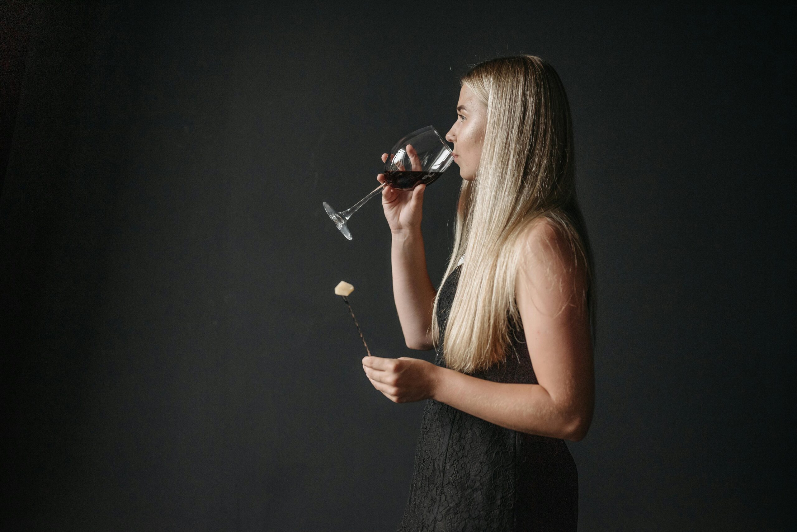 A woman in black dress drinking a glass of wine