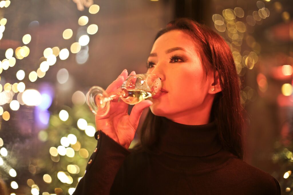 A woman in black drinking a glass of wine