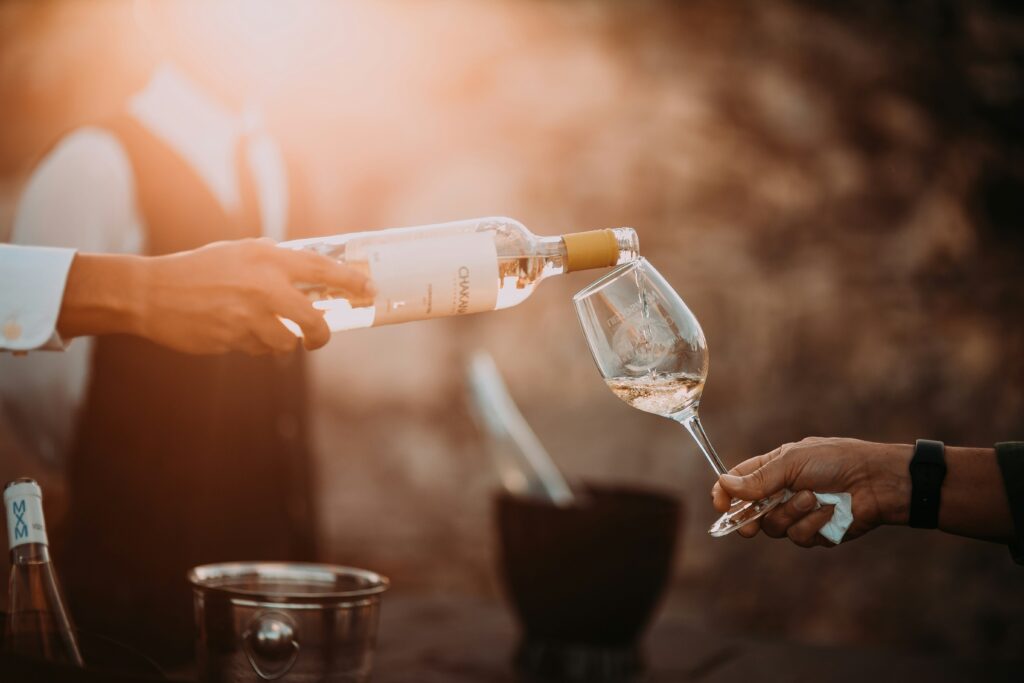 A sommelier pouring a bottle of wine into a glass