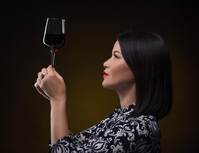 An asian woman staring and inspecting at the wine attentively