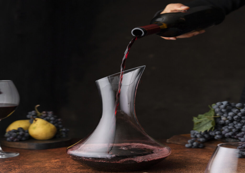 A hand pouring a bottle of wine for decanting