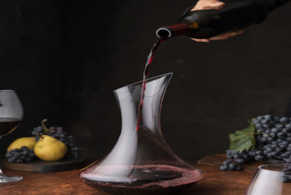 A hand pouring a bottle of wine for decanting